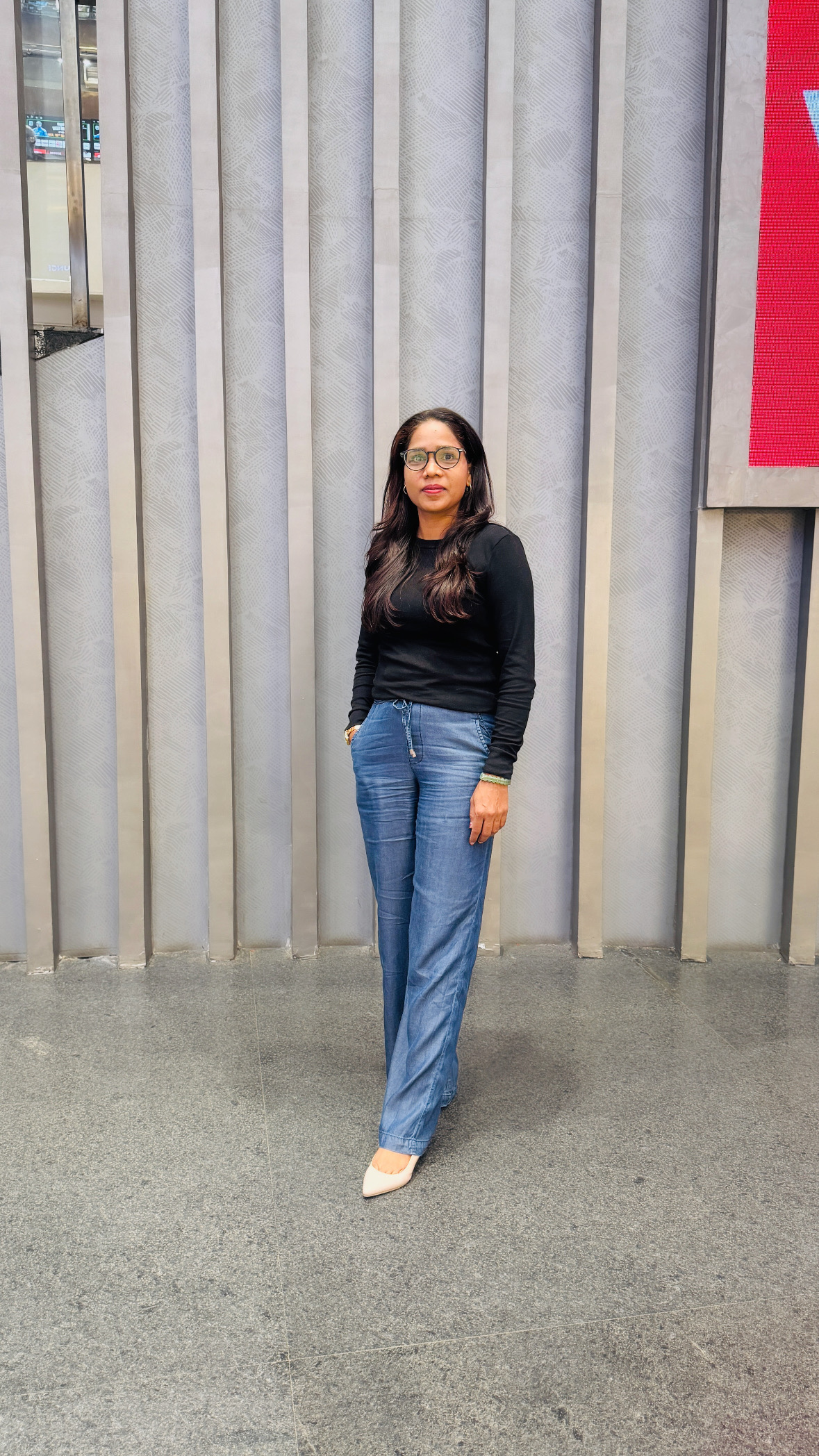 Komal Loat standing in front of an architectural wall